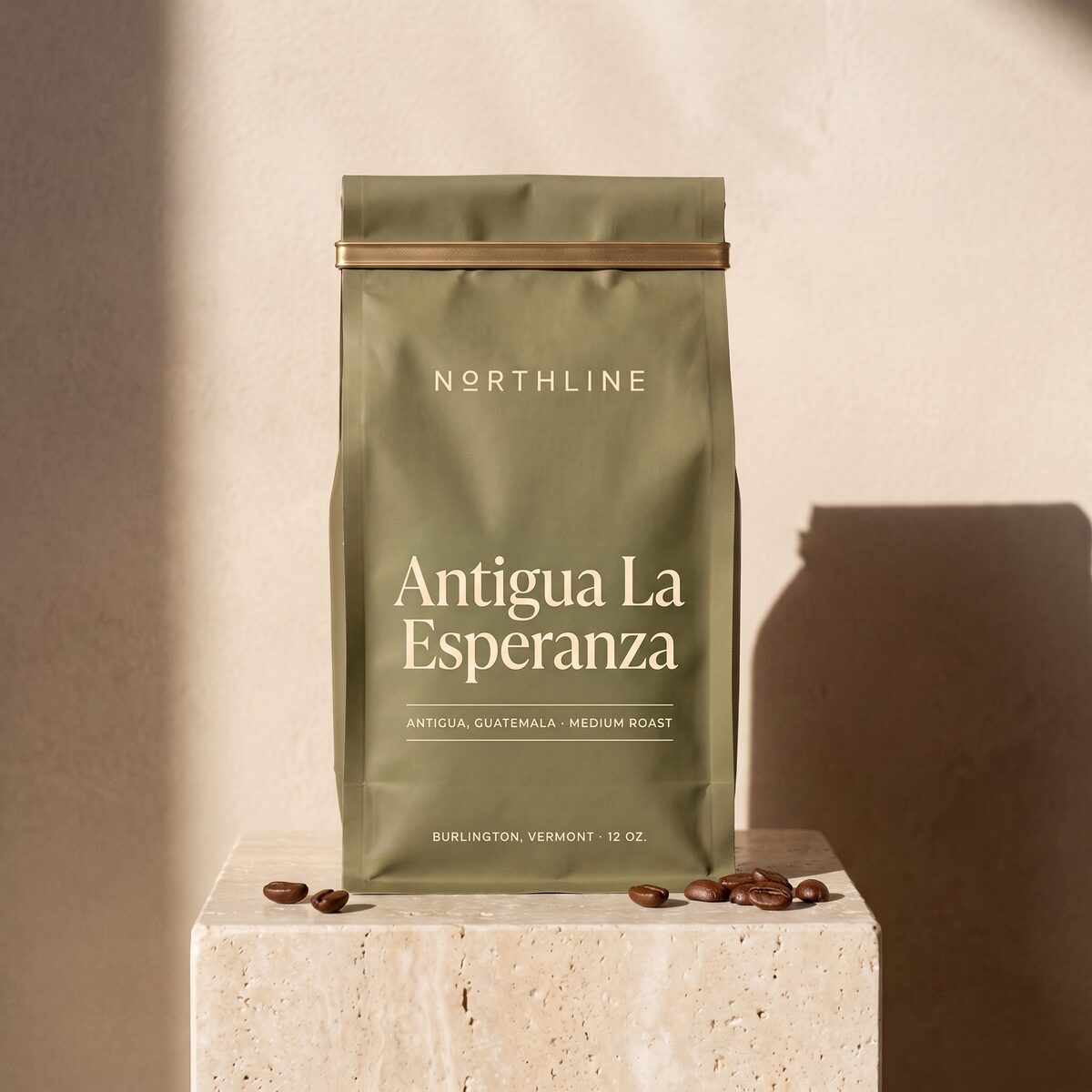 Antigua La Esperanza in a matte olive green Northline coffee bag with a brass tie, on a travertine block against a plaster wall