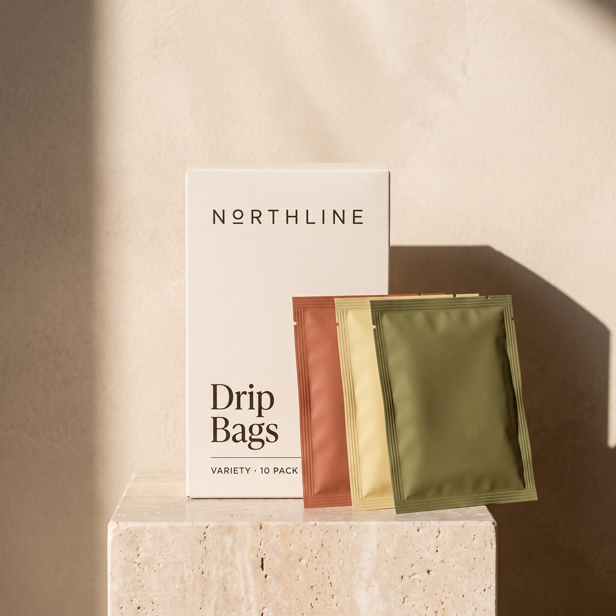 A white Northline box of ten drip coffee bags with three single-serve sachets leaning against it